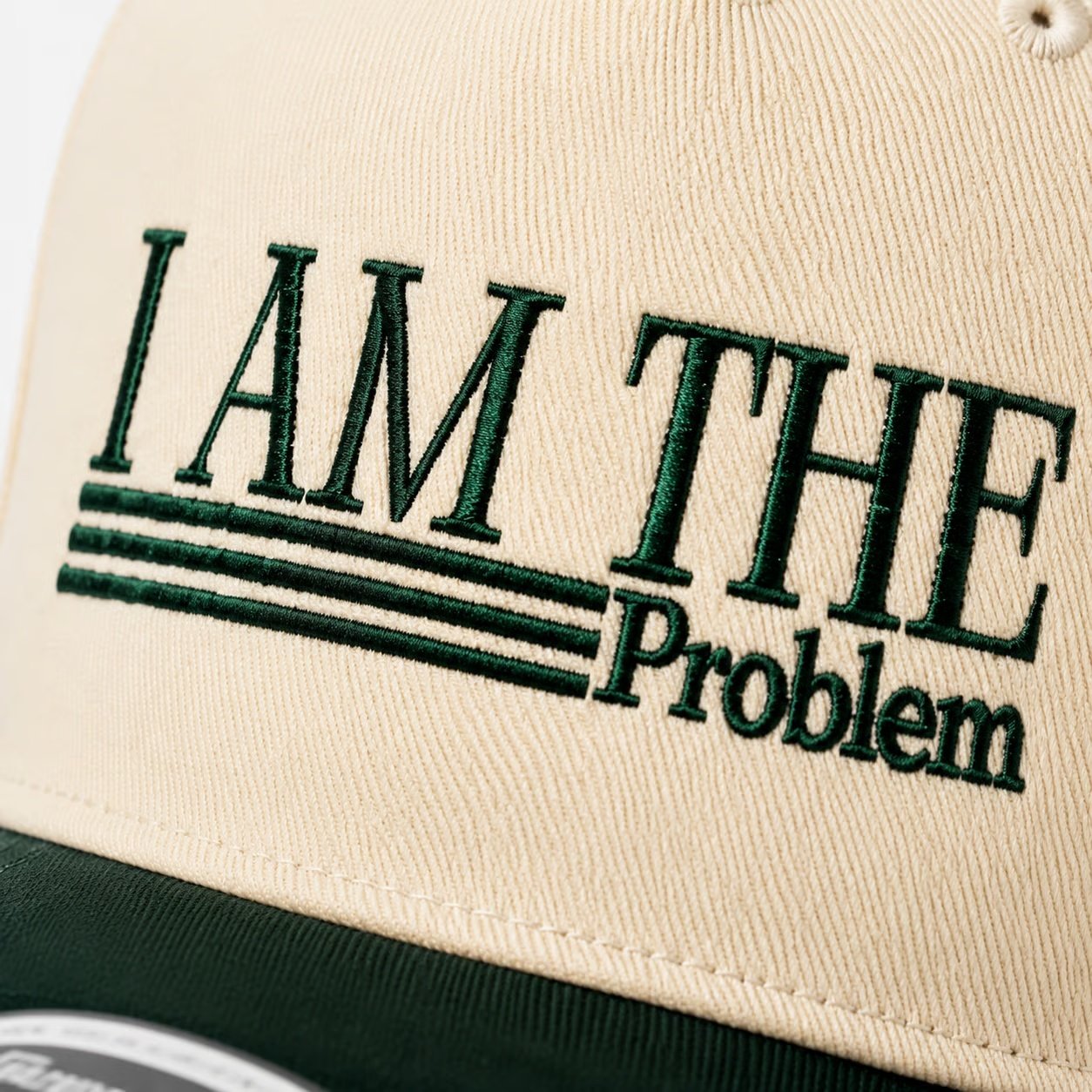 Close-up of dark green embroidery on cream cap
