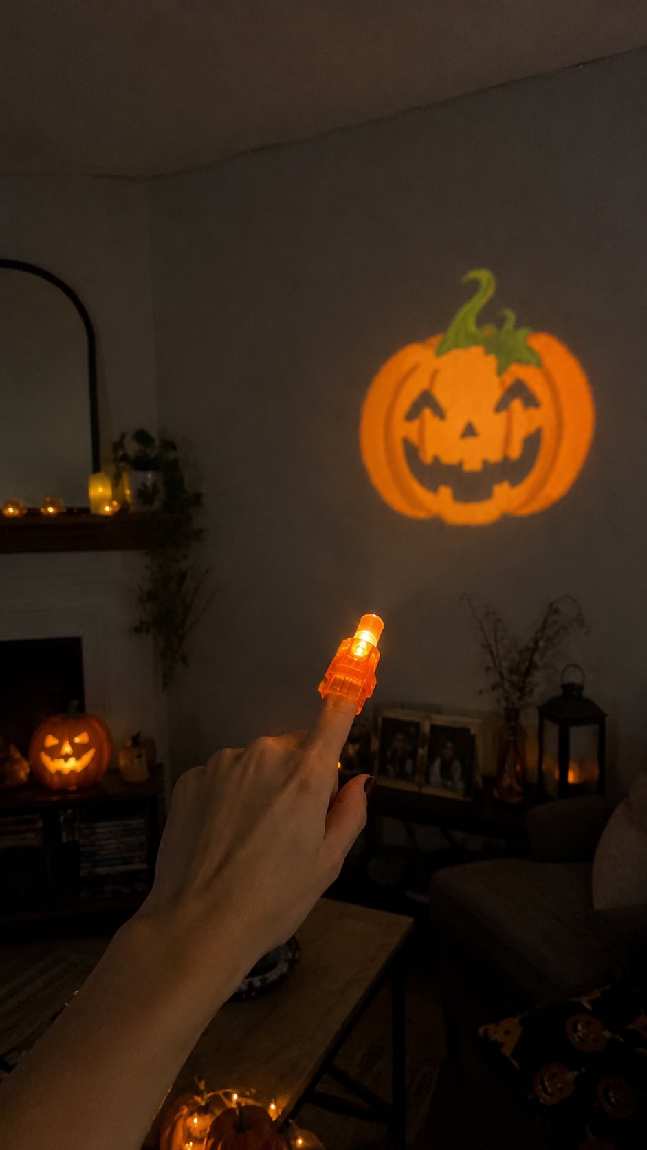 Vertical lifestyle photo of an orange finger projector casting a pumpkin pattern in a Halloween decorated living room Vertical lifestyle photo of an orange finger projector casting a pumpkin pattern in a Halloween decorated living room